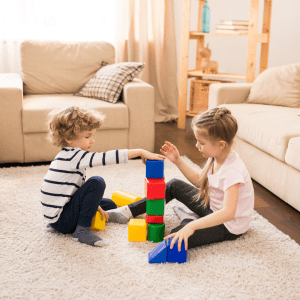 Young boy and young girl playing with blocks on the floor for home-based therapy