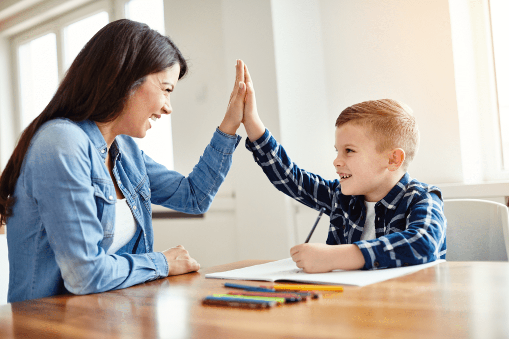 A child smiling while receiving praise from an ABA therapist after successfully completing a skill-building activity.