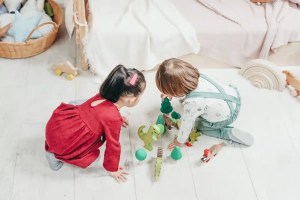 Two kids playing with toys on the floor