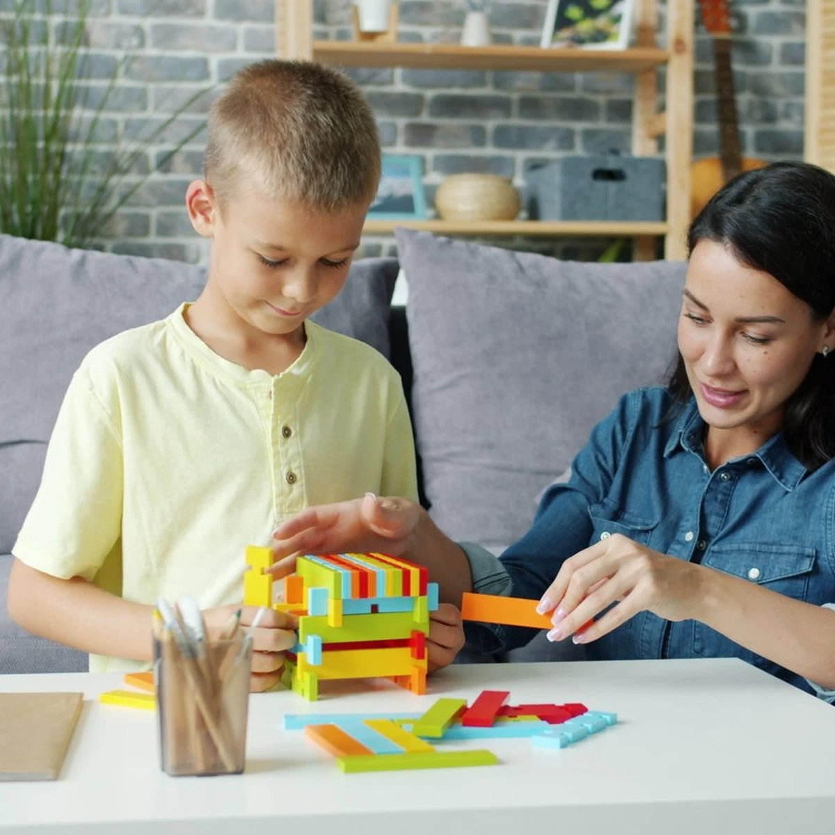 Child practicing a hands-on building activity with a therapist for ABA therapy near me